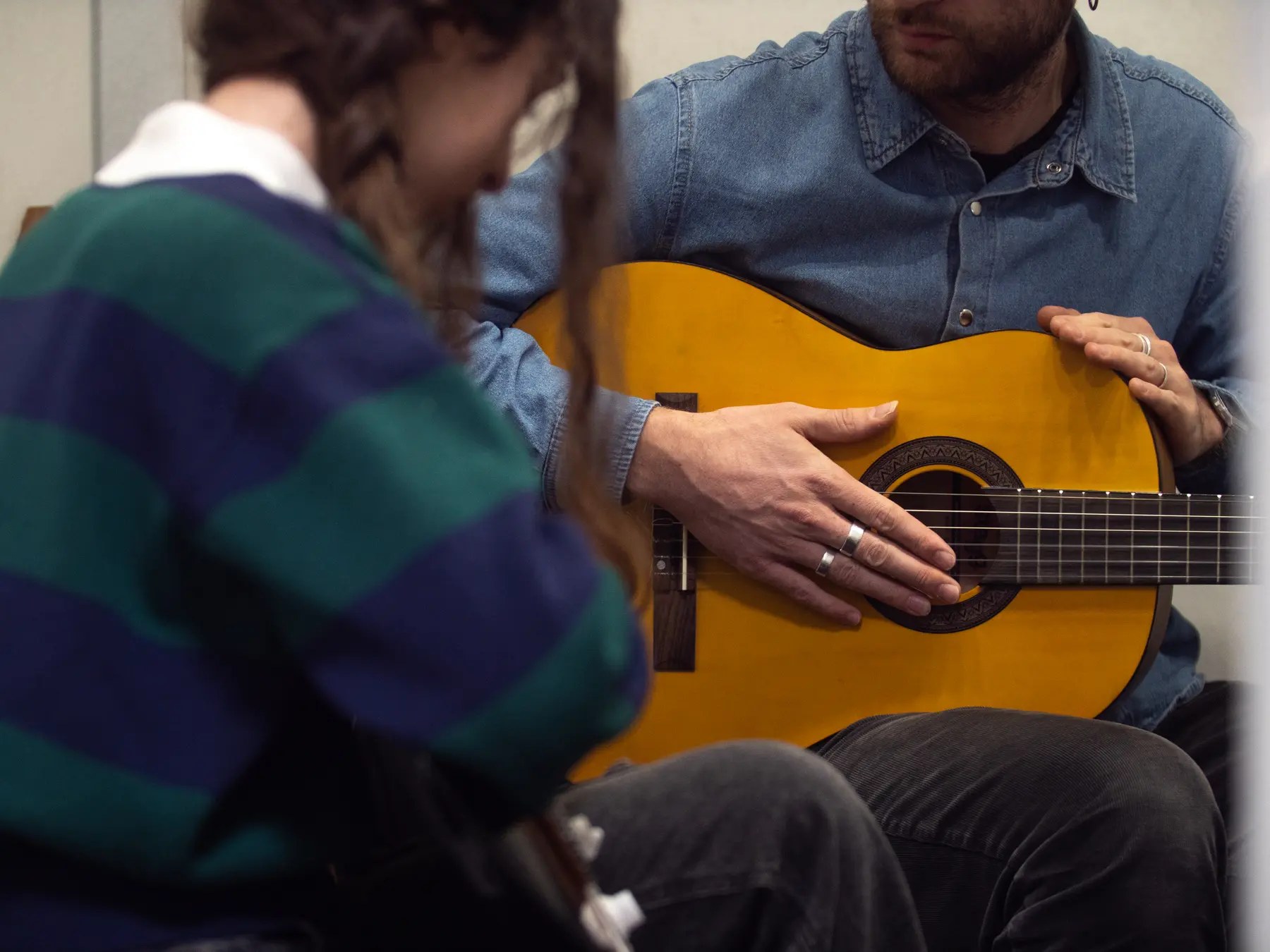 Una lezione di chitarra alla Jam Session, mani sullo strumento in primo piano