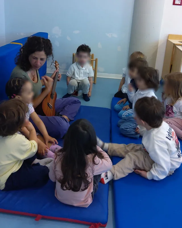 Bambini in cerchio attorno a Stefania che suona l'ukulele